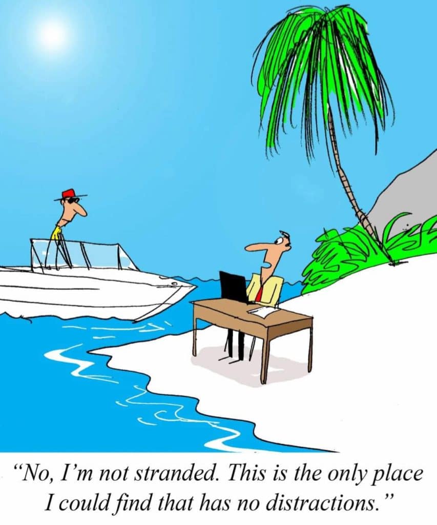Cartoon of a man working on a laptop at a desk on a beach island, telling a man in a boat he is not stranded but avoiding distractions.