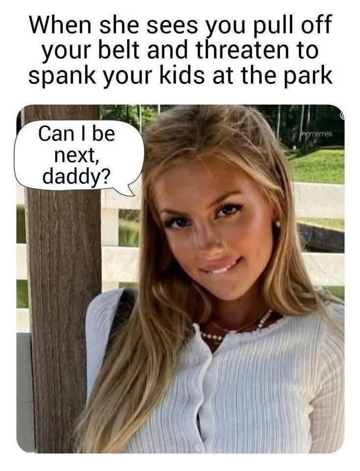A young woman biting her lip with a mischievous smile, outdoors with a wooden fence in the background. Text reads 'When she sees you pull off your belt and threaten to spank your kids at the park' and a speech bubble saying 'Can I be next, daddy?'.