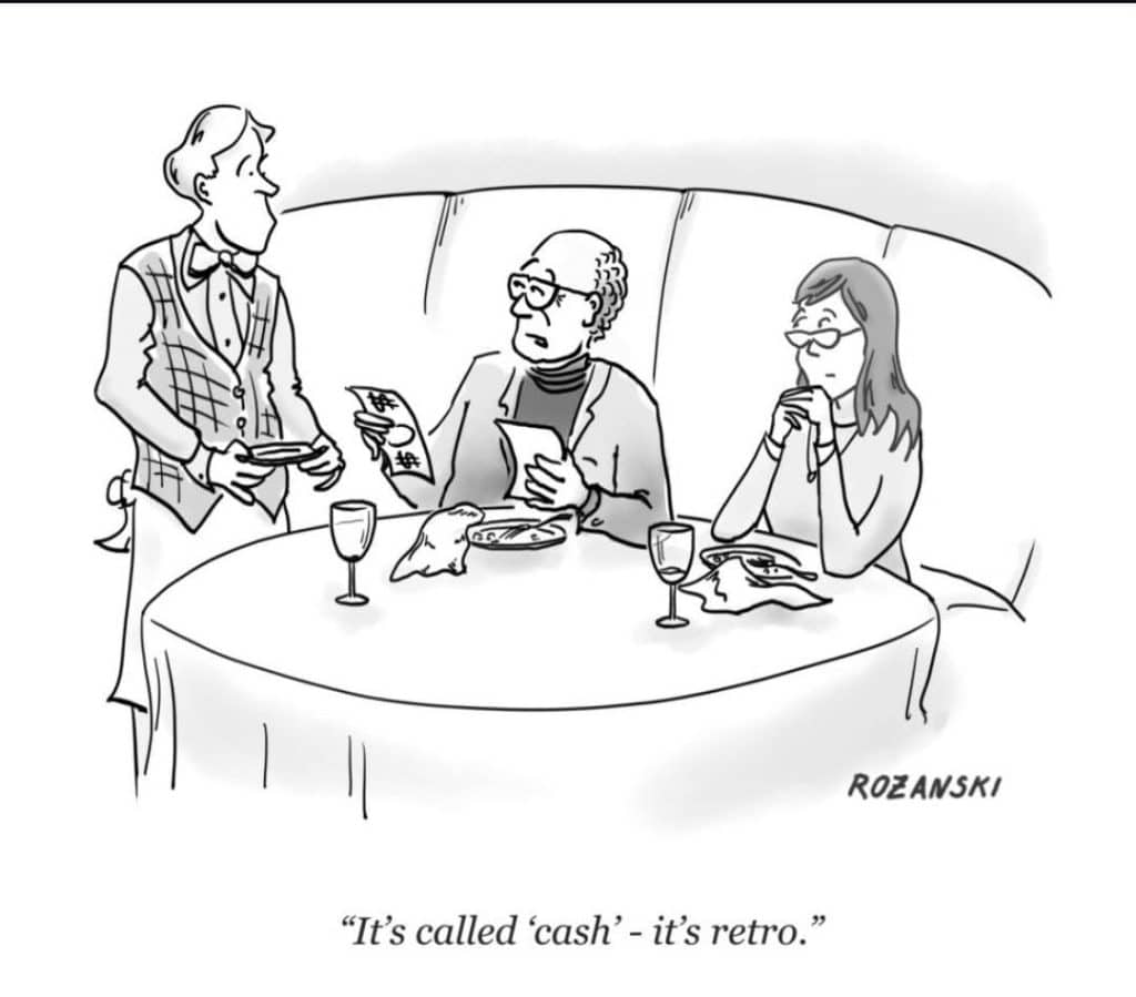 A waiter talking to a man and woman sitting at a table in a restaurant, holding a check and explaining payment.