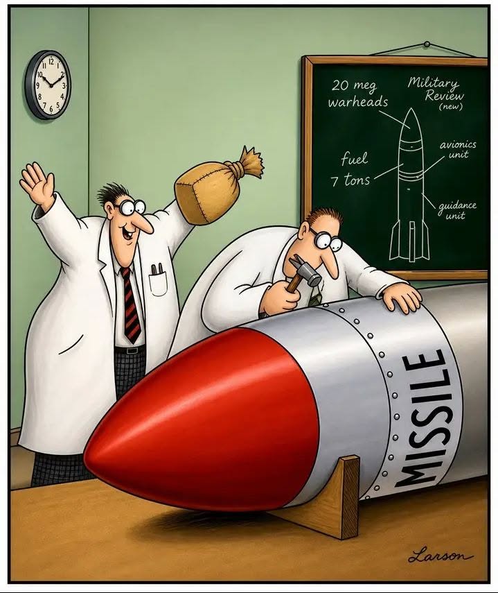 Two scientists in lab coats working on a large missile nose; one uses a hammer and chisel while the other holds a large burlap sack. A chalkboard shows missile parts and labels in the background.