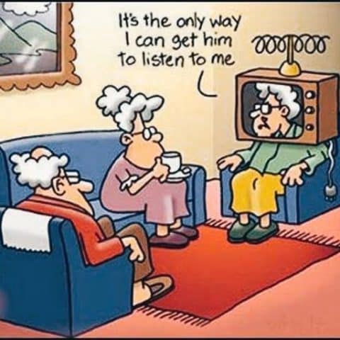 Cartoon of three elderly people in a living room, one woman is sitting with a TV set over her head with an antenna, saying 'It's the only way I can get him to listen to me' while the others sit on couches watching her.
