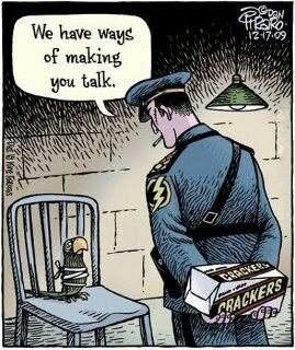 A police officer holding a box of crackers talks to a bird tied to a chair inside a dimly lit room.