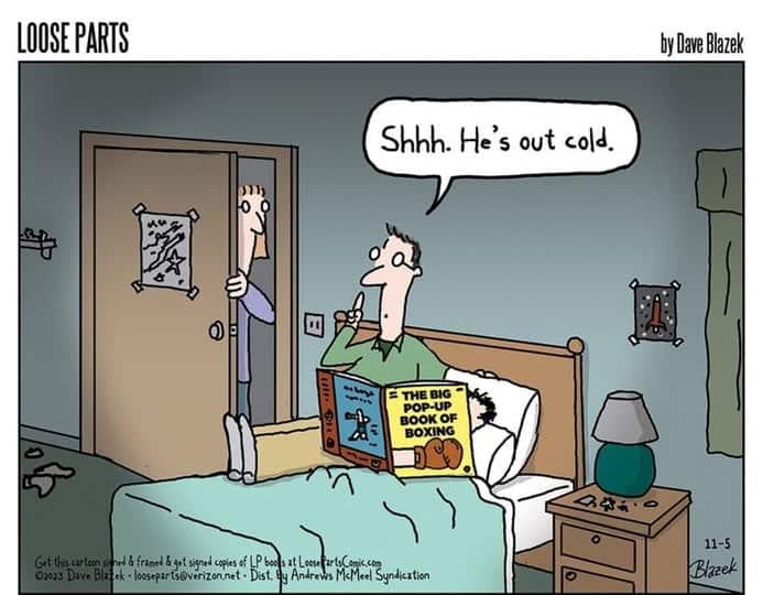 A man sitting on a bed reading 'The Big Pop-Up Book of Boxing' with a finger to his lips saying 'Shhh. He's out cold.' Another person stands in the doorway watching.